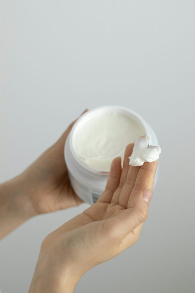 Woman scooping natural hydrating cream from a glass jar – NZ skincare